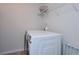 Well-lit laundry room featuring a modern, front-load washing machine, overhead shelving, and neutral wall color at 110 Serendipity Way, Dallas, GA 30157