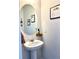 Stylish powder room with a pedestal sink, oval mirror, and tasteful decor, offering a touch of elegance at 110 Serendipity Way, Dallas, GA 30157