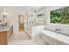 Modern bathroom with marble countertops, soaking tub, glass enclosed shower, and wood cabinets at 1312 Becket Ne Dr, Brookhaven, GA 30319