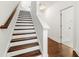 Elegant staircase featuring hardwood steps, white risers, and white walls leading to a bright entryway at 2140 Colvin Nw Ct, Atlanta, GA 30318