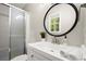 Modern bathroom with a stylish round mirror, white vanity, and a glass-enclosed shower at 505 Samaritan Dr, Cumming, GA 30040