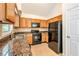Kitchen featuring wooden cabinets, granite counters, black appliances, and tile flooring at 5137 Allison Way, Sugar Hill, GA 30518