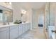 Spacious bathroom with double vanity, neutral tiling, glass shower, and a view into the walk-in closet and additional bedroom at 5415 Trescott Path, Cumming, GA 30028