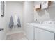 Functional laundry room with washer, dryer, hanging hooks, and a storage basket above the machines at 5415 Trescott Path, Cumming, GA 30028