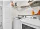Bright laundry room with white front load washer and dryer and storage shelves above at 1350 Rivershyre Pkwy, Lawrenceville, GA 30043