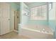 Bright bathroom features a tub, glass shower, decorative shelves, and natural light at 3635 Bardfield Ct, Cumming, GA 30041