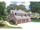 Elegant brick home featuring a three-car garage and meticulously landscaped front yard with lush green lawns and trees at 1720 Monarch Ct, Cumming, GA 30041