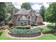 Elegant brick home with a lush front yard featuring tiered landscaping and mature trees at 1720 Monarch Ct, Cumming, GA 30041