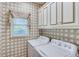 Functional laundry room with patterned wallpaper, cabinetry, and front-loading machines at 1720 Monarch Ct, Cumming, GA 30041
