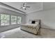 Spacious main bedroom featuring a tray ceiling, fan, plush carpet, and natural light from three windows at 4056 Friendship Creek Dr, Buford, GA 30519