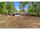 Spacious backyard featuring a brick house, a partially covered patio, and mature trees at 3152 Ridgecrest Dr, Powder Springs, GA 30127