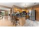 Well-lit kitchen boasts stainless steel appliances, wooden cabinets, tiled floor, and a peninsula island with barstool seating at 1628 Indian Way, Cumming, GA 30040