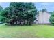 Wide backyard with mature trees and green lawn, with partial view of the home’s exterior, offering a lush outdoor space at 6181 E Fayetteville Dr, Riverdale, GA 30296