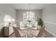 Bright dining room with a round glass table, white chairs, and a modern chandelier at 6181 E Fayetteville Dr, Riverdale, GA 30296