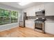 Modern kitchen with stainless steel appliances, gray backsplash, white cabinets, and hardwood floors at 1404 N Crossing Ne Dr, Atlanta, GA 30329