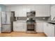 Modern kitchen with stainless steel appliances, gray backsplash, white cabinets, and hardwood floors at 1404 N Crossing Ne Dr, Atlanta, GA 30329