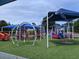 Community playground featuring multiple play structures with shade canopies and artificial grass at 1621 Wellborn Walk, Suwanee, GA 30024