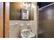 Compact bathroom featuring a traditional sink, tiled walls, and walk-in shower with glass door at 407 E College E St, Bowdon, GA 30108