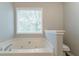 Bathtub area with neutral paint, a tub and a window for natural light at 725 Signature Trce, Palmetto, GA 30268