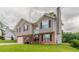 Split-level home shows two-car garage, neutral siding, brick accents, manicured lawn, and charming front entrance at 725 Signature Trce, Palmetto, GA 30268