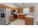 Spacious kitchen featuring stainless steel appliances, wooden cabinets, neutral countertops, and tile flooring at 725 Signature Trce, Palmetto, GA 30268
