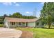 Charming one-story home with a covered porch, green siding, mature trees, and a well-maintained lawn at 107 Bowen Rd, Stockbridge, GA 30281