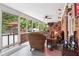 Enclosed sunroom featuring wicker furniture, brick accent wall, and screened windows overlooking lush greenery at 1135 Timberland Se Dr, Marietta, GA 30067