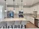Bright kitchen features white cabinets, stainless steel appliances, granite countertops, and a large center island with seating at 1177 Chastain Dr, Sugar Hill, GA 30518
