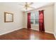 Bedroom with hardwood floors and red curtains features a ceiling fan and a framed mirror on the wall at 3709 Mcguire Nw St, Kennesaw, GA 30144