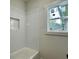 Tiled shower with subway tile and window view in bright bathroom, featuring a built-in niche at 6149 Pinewood Se Dr, Covington, GA 30014