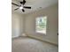 Bright bedroom featuring neutral carpet, ceiling fan, and large window with outdoor view at 6149 Pinewood Se Dr, Covington, GA 30014
