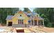 Under construction two-story home with a yellow facade, brick foundation, and black shingled roof at 4545 Greyson Manor Dr, Cumming, GA 30041