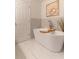 Elegant bathroom featuring a modern bathtub with a wooden tray and marble tile at 607 Hickory Creek Ln, Woodstock, GA 30188
