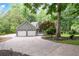 Inviting home featuring a two-car garage and a circular driveway, all surrounded by mature trees and lush landscaping at 1104 Fox Ln, Woodstock, GA 30188