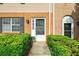 Close-up of townhome entrance featuring brick and siding, black shutters, and manicured landscaping at 406 Northdale Ct, Lawrenceville, GA 30046
