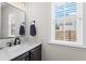 Stylish half-bathroom with a dark vanity, white marble countertop, and ample natural light from the window at 585 Ashland Pkwy, Woodstock, GA 30189