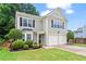 Well-maintained two-story home with a manicured lawn, garden beds, and a two-car garage at 585 Ashland Pkwy, Woodstock, GA 30189