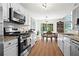 Modern kitchen featuring stainless steel appliances, white cabinets, granite countertops and an adjacent dining area at 585 Ashland Pkwy, Woodstock, GA 30189