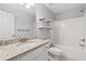 Bright bathroom featuring granite counter, shower-tub combo, floating shelves, and modern fixtures at 2565 Aaron Ct, Loganville, GA 30052