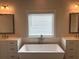 Bright bathroom featuring a soaking tub, white cabinets, double sinks, and a large window at 163 Basil St, Cumming, GA 30040