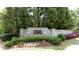 Beautifully landscaped community entrance sign with stone accents surrounded by flowers, greenery, and trees at 3450 Merganser Ln, Alpharetta, GA 30022