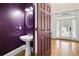 Stylish powder room with elegant purple walls, pedestal sink, decorative mirror and hardwood floors at 3450 Merganser Ln, Alpharetta, GA 30022