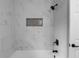 Modern shower with sleek white tiling, niche, and modern fixtures at 7110 Northgreen Dr, Atlanta, GA 30328