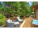 Wooden back deck with seating surrounded by mature green trees at 130 Silver Mist Cir, Alpharetta, GA 30022