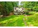 Large backyard featuring a fire pit, lush lawn, and retaining wall with mature trees at 9018 Lakeview Pkwy, Villa Rica, GA 30180