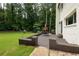 View of a brick patio with outdoor furniture in a spacious backyard with a lush lawn and mature trees at 1908 Musket Ct, Stone Mountain, GA 30087