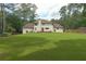 Large backyard with a well-maintained lawn, mature trees, and a charming white house at 1908 Musket Ct, Stone Mountain, GA 30087