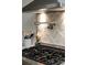 Modern stovetop with pot filler, custom backsplash and stainless steel hood at 1908 Musket Ct, Stone Mountain, GA 30087