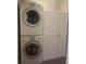Convenient laundry room featuring a stacked washer and dryer with storage cabinets, maximizing space at 1384 N Crossing Ne Dr, Atlanta, GA 30329