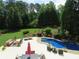 Aerial view of a backyard featuring a pool, landscaped garden, and a patio with outdoor furniture at 154 Gold Leaf Trail Trl, Powder Springs, GA 30127